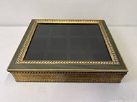 Closed display box showing glass top, gold rope edge, green sides