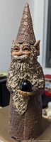 Front view of brown stoneware gnome with black orb