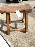 Full view of small rustic bench on pavement