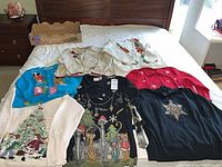 All eight sweaters laid out on bed