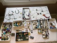 Overview of entire lot on table showing necklaces, bracelets, earrings, pendants