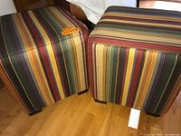 Two Crate & Barrel striped cube ottomans side by side on hardwood floor