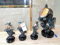 Four turtle sculptures aligned by height beside ruler