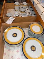 drawer with stacks of salad plates, mugs, saucers, creamer and sugar bowl
