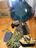 Group shot of umbrella opened with assorted bags, hat, slippers visible