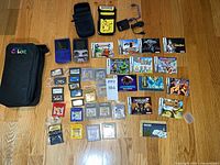 Full layout of lot: consoles, bag, pouches, accessories, boxed games and loose cartridges