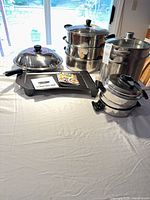 Overall grouping of griddle, stock pot, steamer set, wok and saucepan