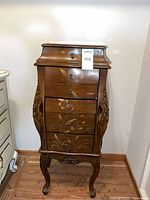 Full view of wood jewelry armoire with drawers and side carvings