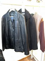 Three jackets on hangers: leather, wool, Lacoste