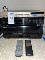 Stacked view of DVD player, mic mixer, stereo receiver with two remotes in front