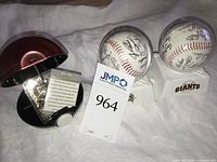 Overview of gold plated Pokémon card in Poké Ball with COA alongside two signed baseballs on stands