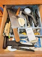 Open drawer with assorted knives, utensils and tools