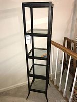 Full view of black metal display shelf with glass shelves