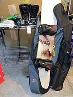 Full view of snowboard in bag with boots, goggles, hat, gloves on shelf