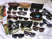 Full lot overview showing all sunglasses, cases, soft pouch and auction tag