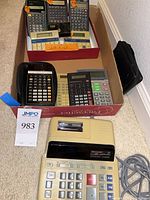 Lot overview showing Sharp printing calculator and box with eight handheld calculators