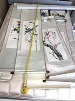 Three scrolls unrolled on mattress with tape measure showing length