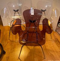 Front view showing three acrylic armchairs, two clear and one smoked amber, with chrome legs