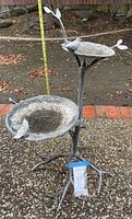 Full view of two-tier cast metal birdbath with measuring tape showing height
