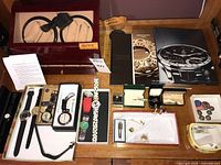 Overall lot showing watch winder, watches, pins, tie clips and booklets