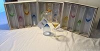 Three open boxes each holding four multicolor stemware pieces plus two loose glasses