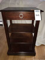 Full view of dark wood side table showing drawer, two shelves, and overall design