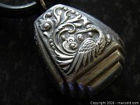 Close-up of silver rattle showing Phoenix and foliate relief.