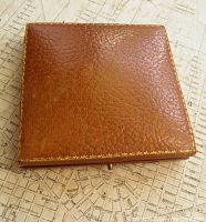 closed brown leather medal case, stitched gilt edges