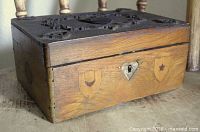 Three-quarter front view showing carved lid, inlaid front shields, lock escutcheon