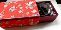 Red floral Asian-style box partially open showing necklaces inside