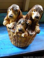 Front view showing three basset hound puppy heads over basket rim