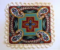 Full view of square beaded cover with loop fringe