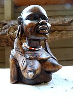 Front view of carved hardwood bust showing facial features, bead necklace, patina