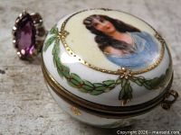 Sterling silver ring beside porcelain box showing portrait lid and gemstone colour