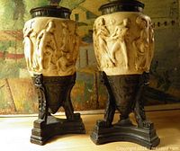 Pair of urns front view showing relief figures and tripod bases