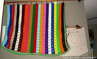 Full view of crocheted blanket hanging, showing size and stripe pattern
