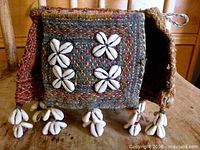 Front view showing embroidered wool panel with cowrie shell flower motifs and tassel fringe