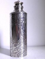 Upright view of sterling scent bottle showing repousse pattern and blank cartouche
