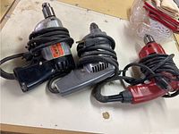 Three corded drills coiled with power cords