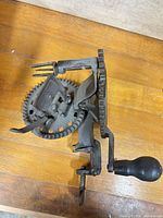 Full view of cast iron apple peeler showing gears, prongs and wood handle