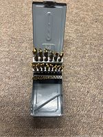 Open case displaying two indexed rows of gold-tone drill bits