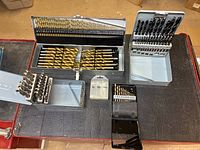 Overview of all five drill bit sets in their cases on workbench