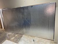 Full view of one foil-faced insulation board leaning against wall