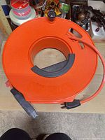 Front view of orange plastic extension cord reel showing center grip and cord