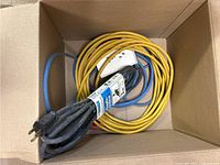 Coiled yellow extension cord and other cords in box