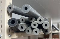 Group of foam insulation tubes on shelf showing hollow cores and varying diameters