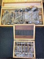 Two wooden boxes containing multiple Forstner drill bits under plastic wrap