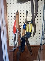 Hand tools on pegboard including trowel, cultivator, weeder, shears, pruner