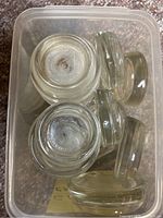 Clear glass furniture guides stacked in plastic bin