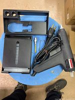 Top view of glue gun, cord, plug, plastic holder sections, spare nozzle, wire stand, glue stick